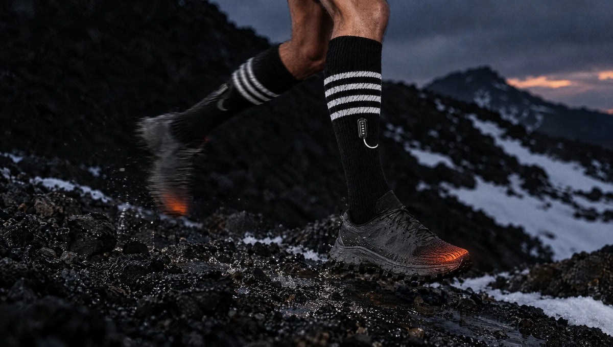 Runner on dark scree in striped heated socks with the toe heat glowing