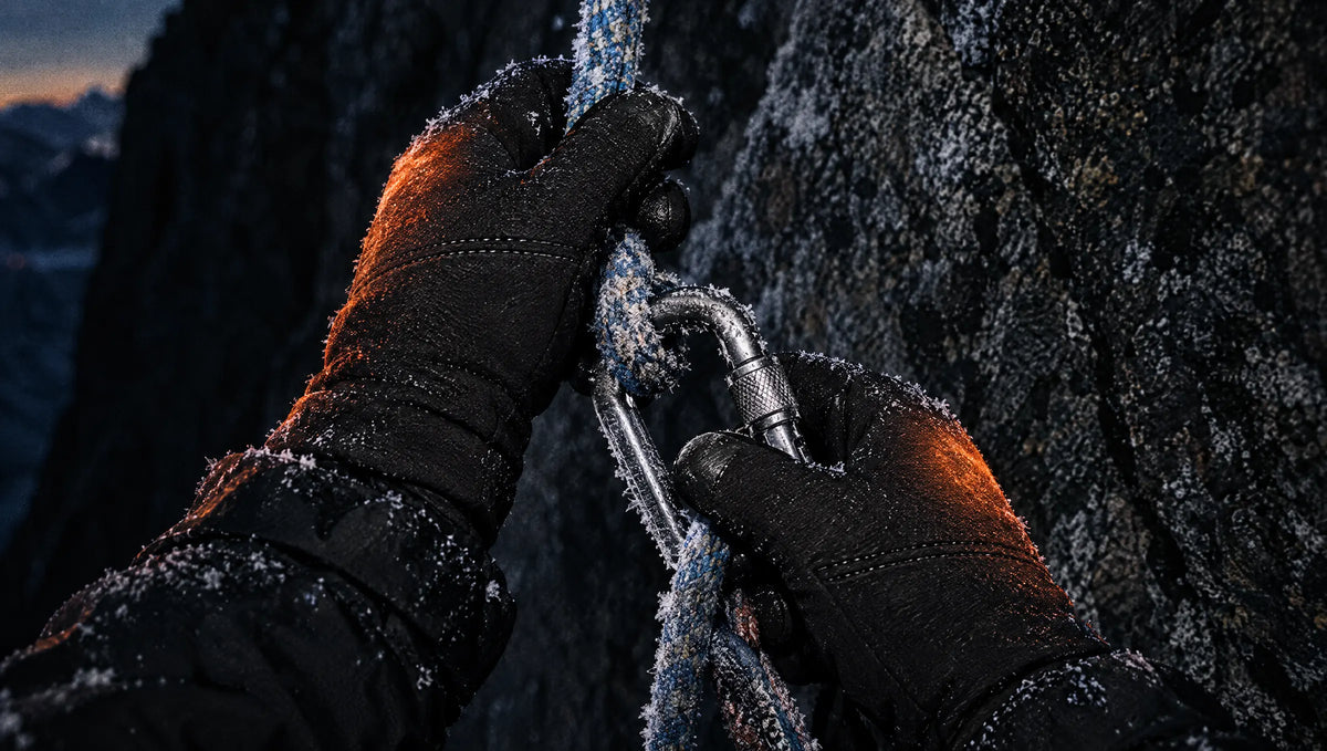 Gloved hands with glowing heat gripping a rope and carabiner on cold rock