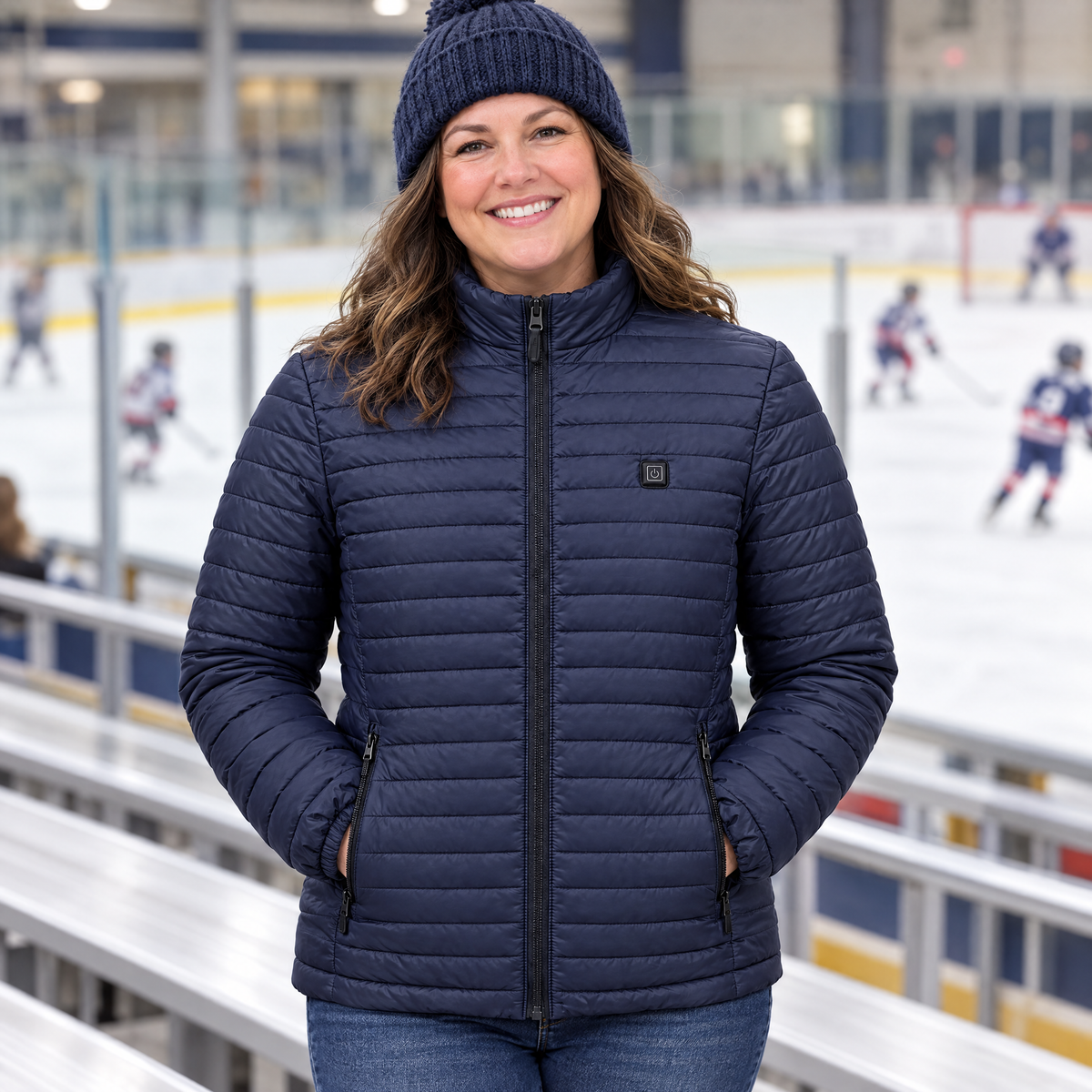 Hockey mom at an ice rink wearing the Basecamp women's heated jacket in navy, hands in the heated pockets
