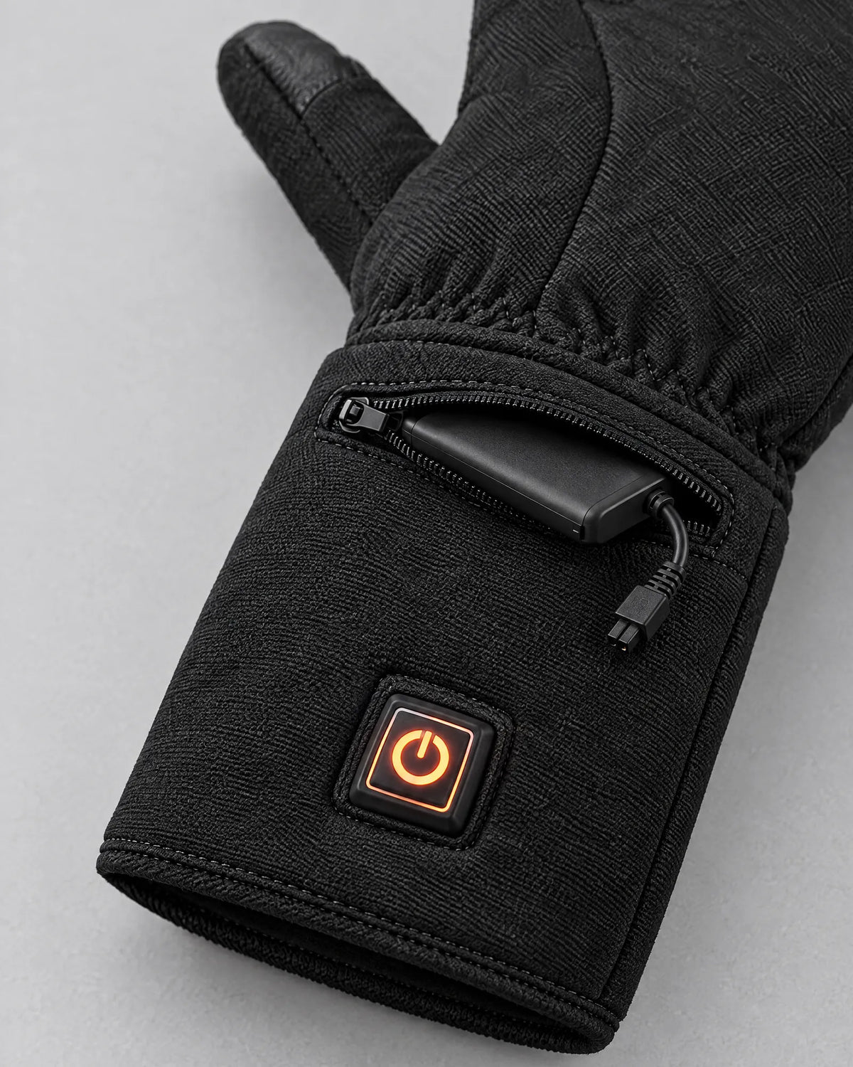 Zipped cuff pocket of the Belay glove with the battery and glowing button