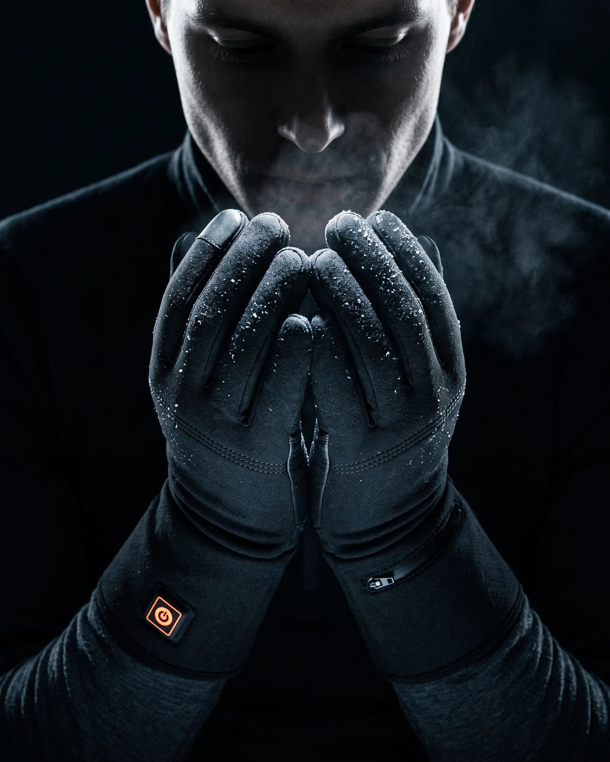 Hands in Belay heated gloves cupped below the chin, frost on the knuckles