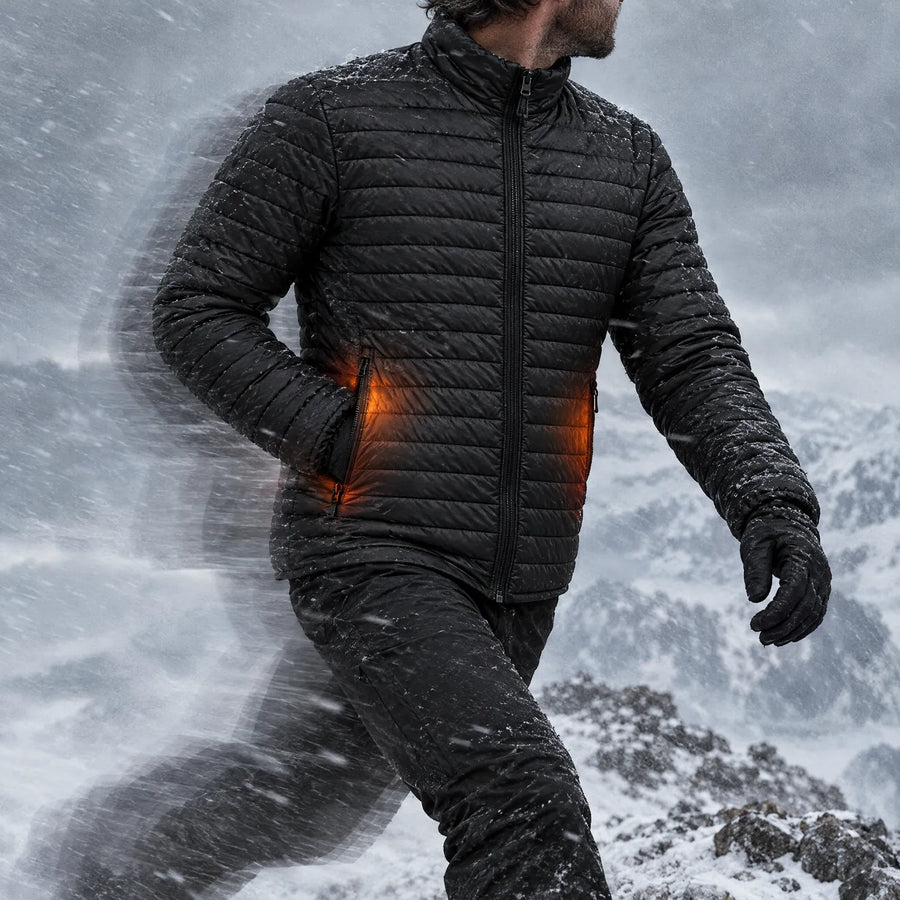 Man striding into the wind on a snowy ridge in the Basecamp men's heated jacket, pocket heat glowing