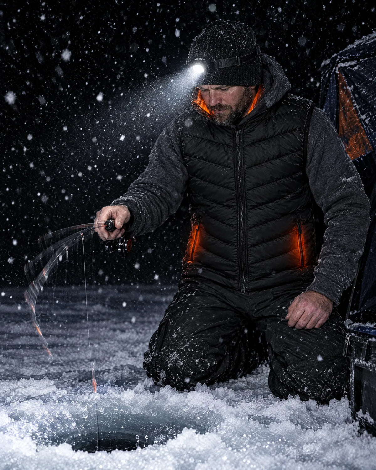 Ice angler at night wearing the Treeline heated vest over a hoodie