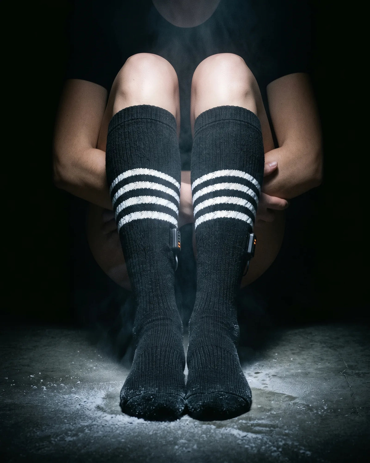 Legs in Switchback heated knee-high socks on a frosted floor, lit from above