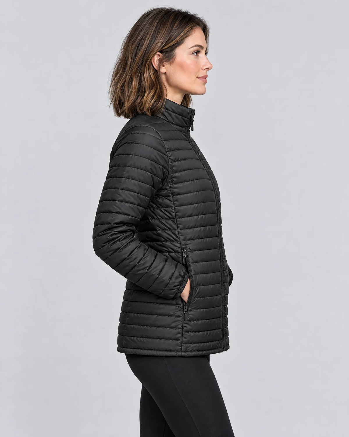 Model wearing the Basecamp women's heated jacket, side view with hands in pockets